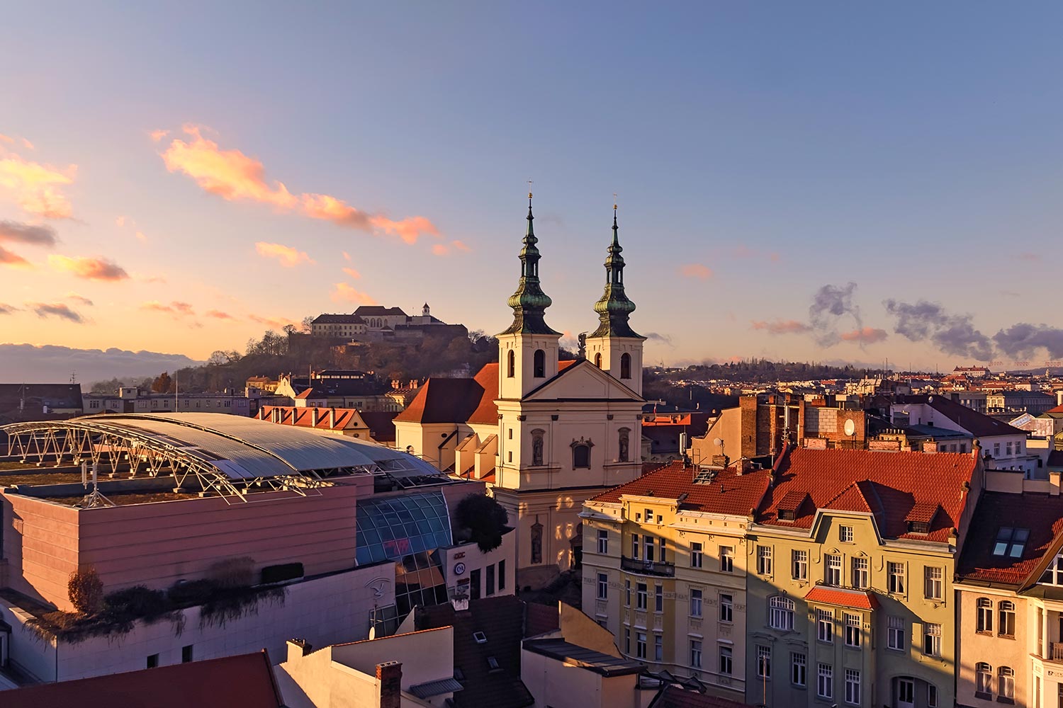 Brno, Czech Republic. View of the city at sunset, church with two steeples at the center of the photo.